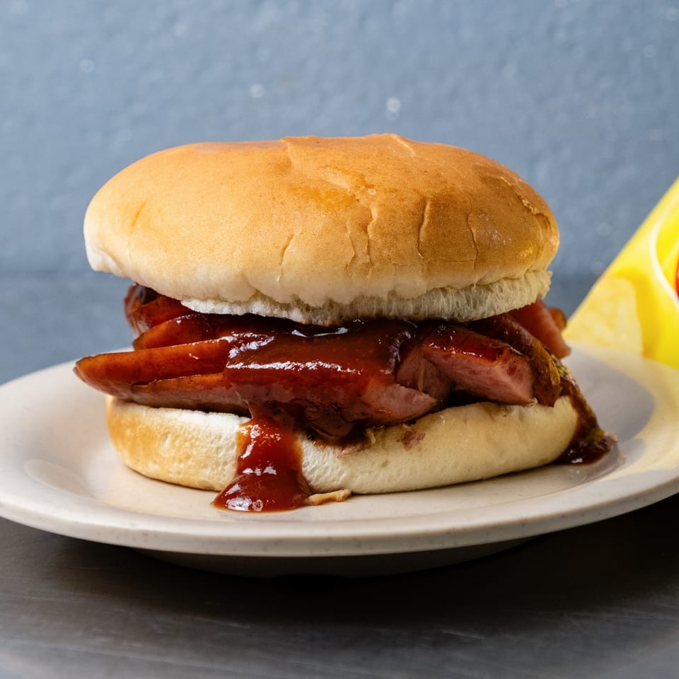 A Junior's Barbeque sandwich with sliced meat and barbecue sauce on a white bun.