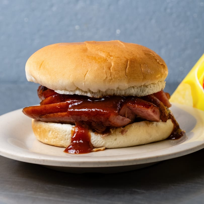 A Junior's Barbeque sandwich with sliced meat and barbecue sauce on a white bun.
